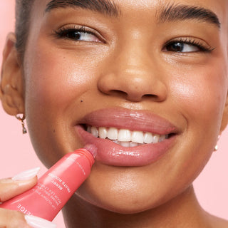Woman applying pink lip balm with a pink background