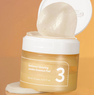 Numbuzin No.3 Radiance Glowing Jumbo Essence Pad showing a close-up of the large, soft cotton pad with product packaging in the background.